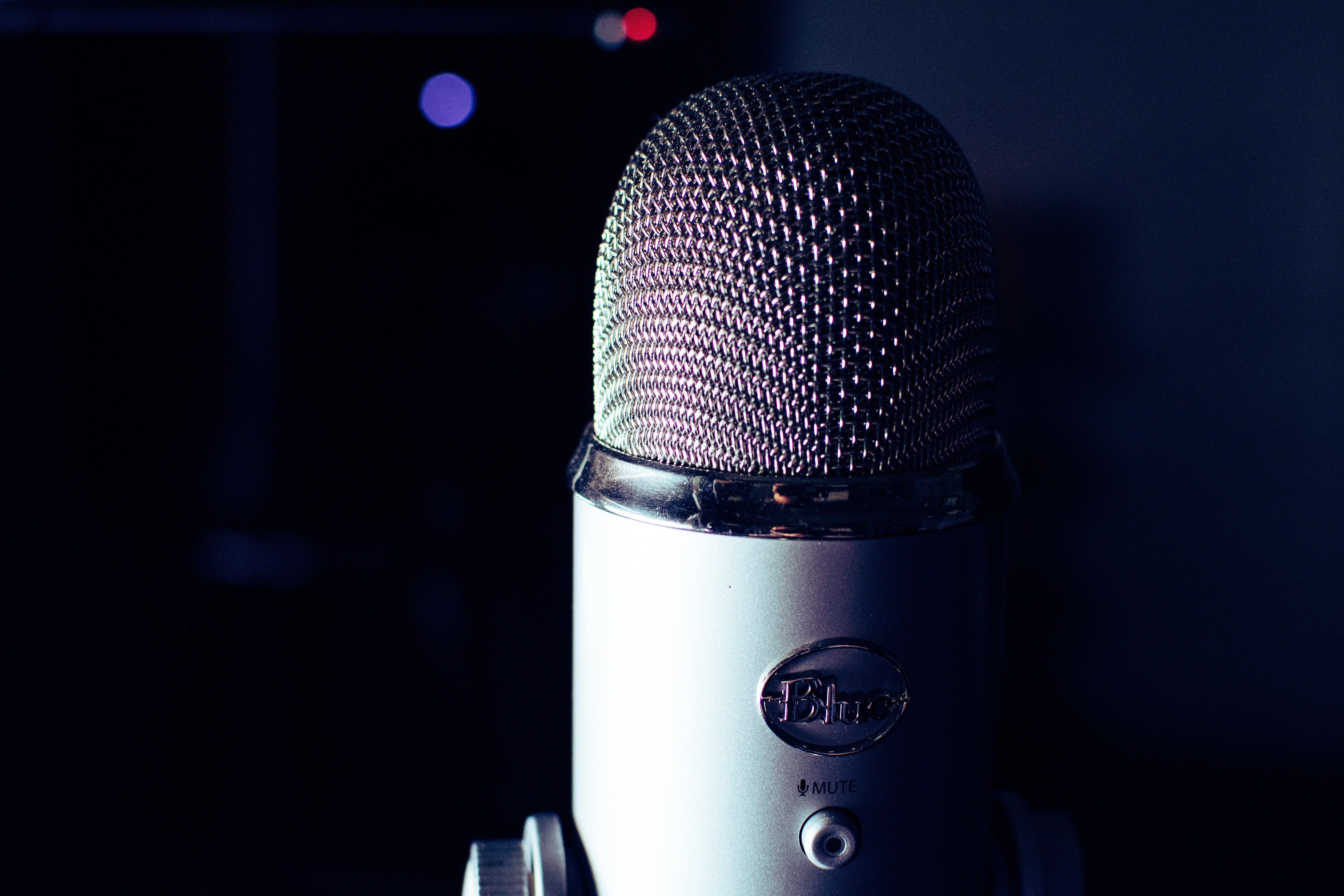 Close up of dark grey coloured condenser microphone, in front of luminous dark blue background