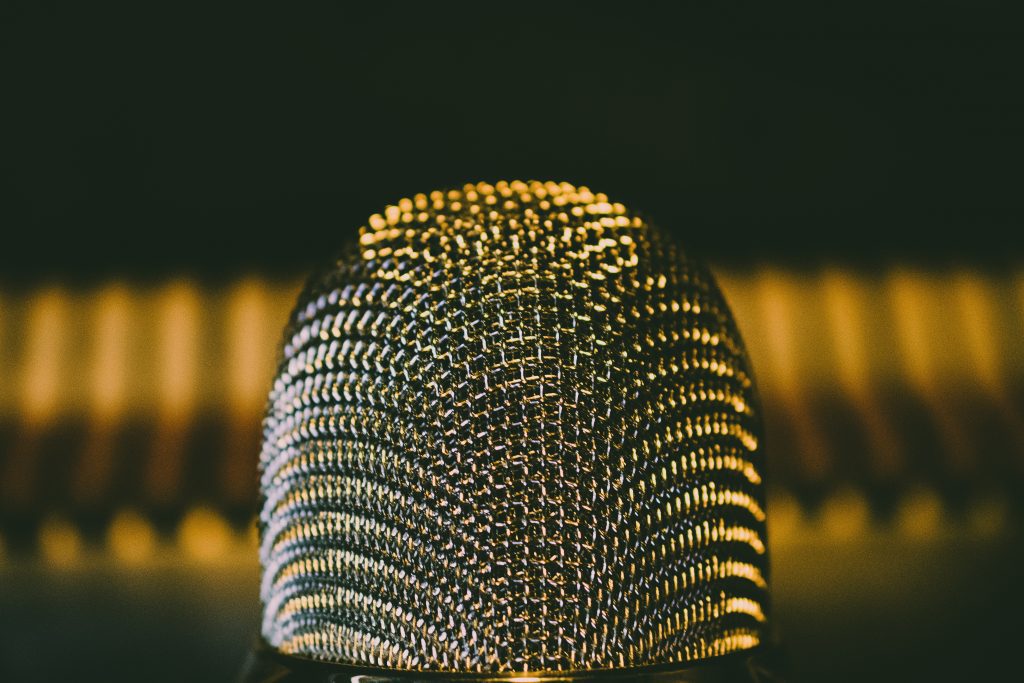 Warm gold tone lighting reflecting on extreme close up of steal microphone 