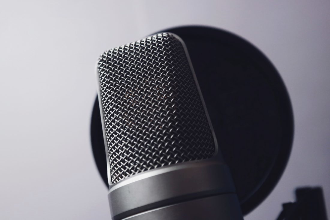 Grey tone image of Silver Condenser Microphone, in front of wind pop filter